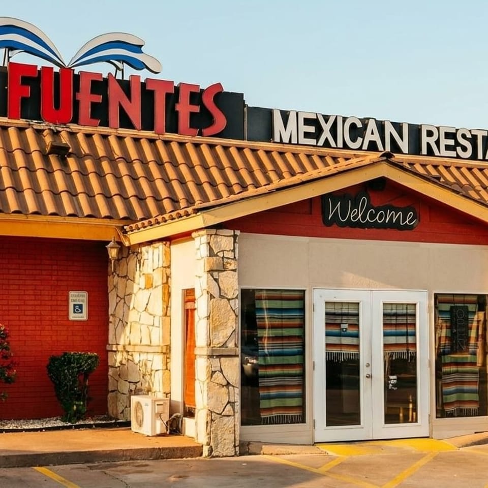 Exterior of Las Fuentes Mexican Restaurant with red brick, stone accents, and a "Welcome" sign.
